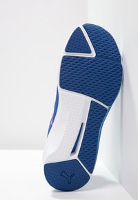 Athletic shoe sole with blue rubber material, textured surface, triangular and rectangular patterns, and white accents. PUMA logo located on heel.