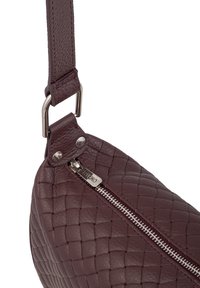 Borsa in pelle bordeaux con texture intrecciata, zip argentata e accessori metallici. Tracolla regolabile che si collega a un anello rettangolare.