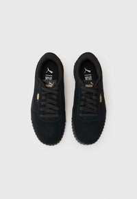 Black suede sneakers with textured laces, rounded toe, cushioned interior, and rubber outsole. Features a gold logo on the side.