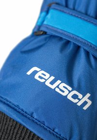 Blå skidhandske med en texturerad tyg, elastisk handled med ett blått band och en framträdande vit "reusch"-logotyp på sidan.