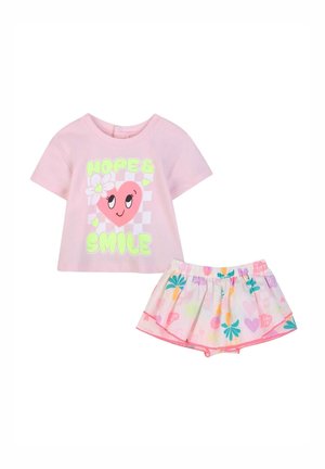 Completo rosa per bambina con maglietta grafica a cuore "Hope & Smile" e gonna colorata con motivo floreale e cintura elastica.