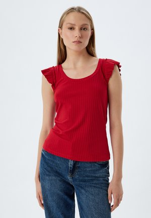 Rotes, geripptes Tanktop mit fließenden Schulterakzenten, figurbetonter Passform und runder Halslinie, kombiniert mit blauen Jeans.