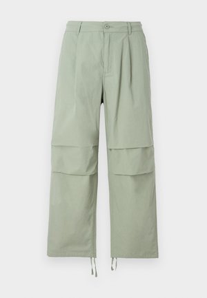 Light green cargo pants with a loose fit, featuring front pleats, two large pockets, and drawstring hems for adjustable length.
