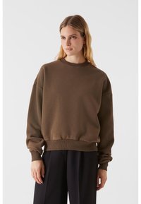 Sweatshirt maro cu guler rotund. Croială lejeră, mânici și tiv cu nervuri, textură moale. Purtați-l cu pantaloni negri cu talie înaltă.