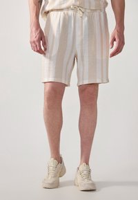 Shorts de mezcla de lino en crema con rayas verticales de un beige claro, con una cintura elástica y cordón, acabados con dobladillos enrollados.