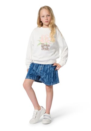 Sweat-shirt blanc avec motif floral, logo "Kenzo Paris" ; associé à un short en jean bleu avec un imprimé à motifs ; baskets blanches à scratch.