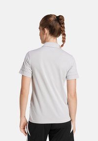 Lichtgrijze polo met een zachte textuur, korte mouwen en een omgeslagen kraag. Heeft een rechte achterkant en zijsplitten voor bewegingsvrijheid.