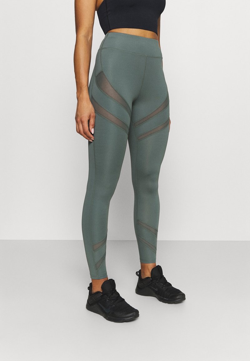 Legginsy z wysokim stanem w oliwkowym kolorze, z przezroczystymi panelami z siateczki i eleganckim, dopasowanym krojem. Wykonane z elastycznej, gładkiej tkaniny.