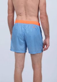 Shorts de bain bleus avec une taille élastique orange, présentant un motif géométrique et des poches latérales. Tissu léger et lisse, design longueur genou.