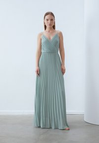 Pleated maxi-mekko vaaleansinivihreästä kankaasta, jossa on spagettiolkaimet ja syvä V-pääntie. Virtaava siluetti, jossa on vartalonmyötäinen vyötärö.