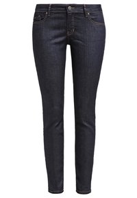 Jeans skinny de mezclilla azul oscuro con cintura media, diseño de cinco bolsillos y sutiles acentos de costura a lo largo de las costuras. Textura suave.