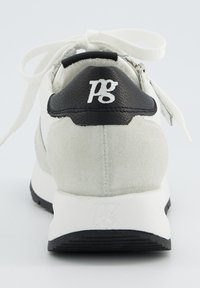 Baskets en daim blanc avec un passant de talon en cuir noir et des lacets blancs. Présente un dessus texturé et un logo en relief sur le talon. Semelle noire.