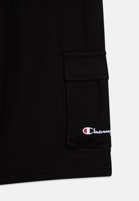 Crne cargo kratke hlače izrađene od pamučne tkanine s dodatkom. Imaju bočnu džep i izvezeni "Champion" logo u bijeloj i crvenoj boji.