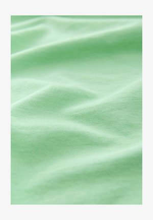 Ljusgrön tyg med en slät textur, som har subtil ribbning och veck, vilket ger ett mjukt och andningsbart utseende.