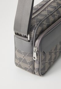 Borsa a tracolla grigia con tessuto a motivo geometrico, dettagli in pelle testurizzata, hardware in argento e chiusura con zip.