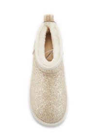 Scarpa slip-on dorata scintillante con morbida fodera in pelliccia bianca e un tab arricciato beige. Punta rotonda e piatta e suola robusta bianca per il comfort.