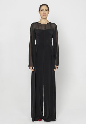 Czarny kombinezon z długimi przezroczystymi rękawami, dopasowaną górą i szerokimi, płynącymi nogawkami. Ma okrągły dekolt i gładką teksturę.