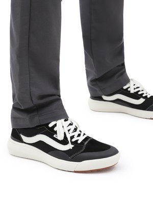 Sneakers in bianco e nero realizzati in suede e materiale a rete, punta tonda, lacci bianchi e suola in gomma testurizzata; visibili accenti di design specifici.