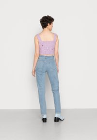 Top cropped em estilo de crochê na cor lavanda com flores bordadas, combinado com jeans de cintura alta azul-claro e mules de salto azul.