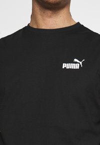 T-shirt a maniche lunghe nera in cotone con logo PUMA bianco sul petto. Il tessuto è liscio e presenta un classico collo a giro.