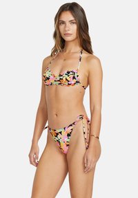 Kvetinový bikiny set s čiernym základom a farebnými kvetinovými vzormi. Vrchná časť má nastaviteľné ramienka a spodná časť sa viaže po stranách.