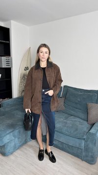 Brun semsket jakke med svart krage, kombinert med svart topp og denimskjørt. Sorte loafers og en liten svart håndveske fullfører antrekket.