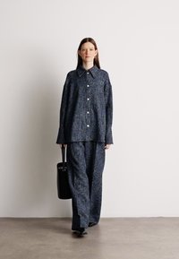 Camisa oversized azul-marinho com padrão, acompanhada de calças a condizer, feita de tecido texturizado, com frente abotoada e colarinho pontiagudo.