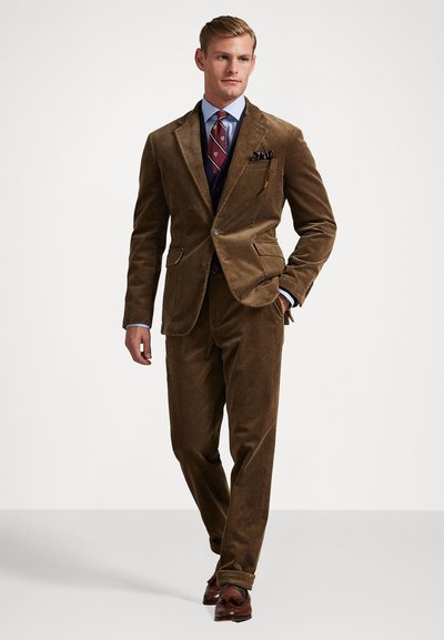 Costume en velours côtelé marron au design ajusté, avec un col cranté, deux poches avant et un tissu texturé. Associé à une chemise habillée bleue et une cravate à motifs.