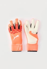 Målvaktshandskar med en orange och krämfärgad design, utrustade med texturerat grepp på fingrarna, elastiskt handledsband och svarta detaljer.