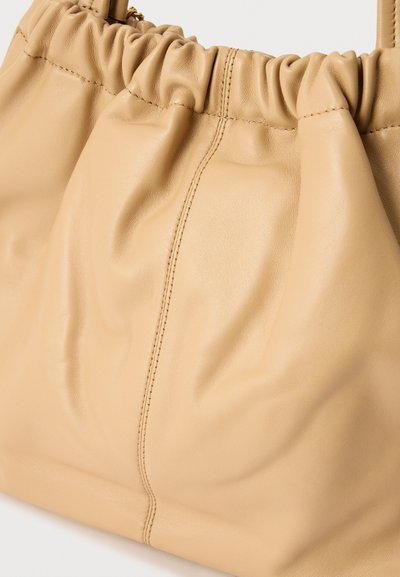 Τσάντα ώμου από δέρμα ταμπά με επάνω άκρο που συγκεντρώνεται, διπλές λαβές και εμφανές κάθετο ράψιμο στο κέντρο μπροστά.