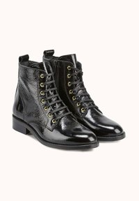 Bottines noires à finition brillante et texturée, avec œillets dorés, lacets noirs et talon bloc bas.