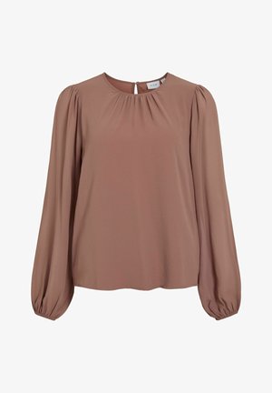 Pruun bluus, mis on valmistatud siledast kangast, ümarate kaelustega, pleeditud esiosa ning pikkade ballooni varrukatega, millel on kitsad mansetid. Seljal võtmeauk.