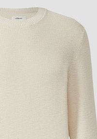Cremefarbenes gestricktes Sweatshirt mit runden Ausschnitt, das ein strukturiertes Muster und gerippte Bündchen aufweist. Markenlabel am Kragen sichtbar.