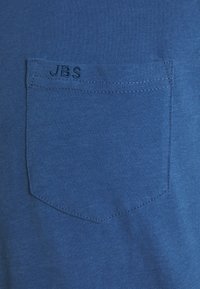 Blå bomulds t-shirt med en lille lomme, som har en broderet "J.B.S." detalje. Stofkvaliteten er glat med et afslappet design.