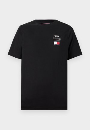 Maglietta nera a maniche corte con collo rotondo, con i loghi della Cadillac Formula 1 Team e Tommy Hilfiger sul petto in alto a sinistra.