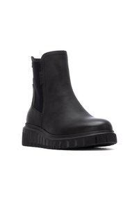 Stivaletto nero realizzato in pelle sintetica con pannelli laterali elastici, dotato di una suola spessa e scanalata per trazione e stabilità.
