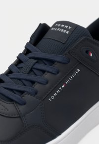 Baskets bleu marine Tommy Hilfiger avec logo de la marque sur le côté et la languette, dotées de lacets bleu foncé et d'une semelle blanche.