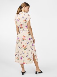 Robe midi florale en tissu beige doux, dotée de manches courtes, d'une ceinture à la taille et d'une fente sur les côtés, avec des motifs floraux multicolores.