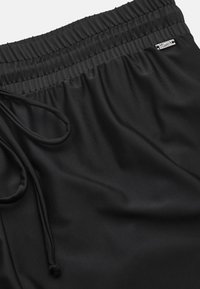 Svarta sportshorts i ett mjukt tyg, med resårmidja, dragsko och en liten detalj med silverlogga.