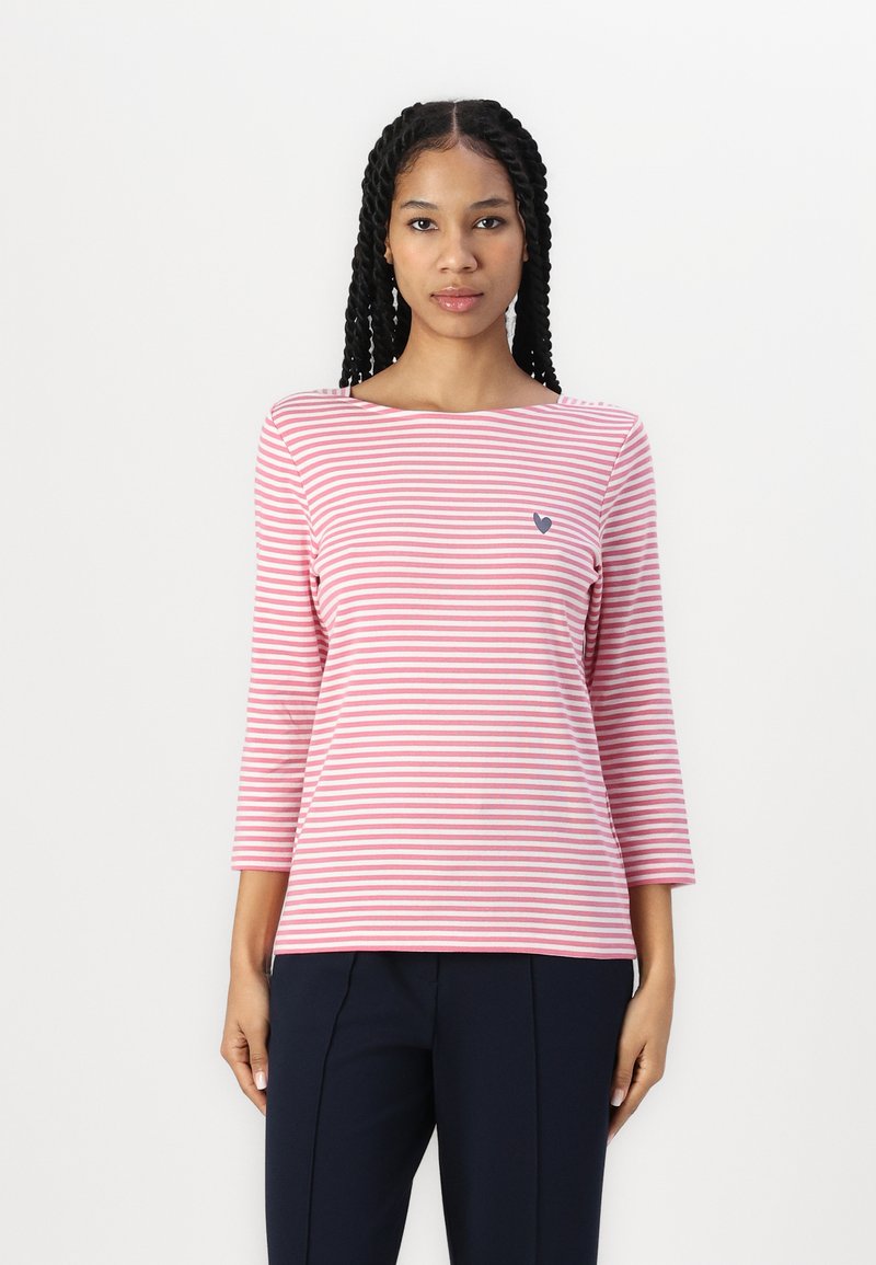 Rosa og hvit stripet langermet topp med båtutringning og en liten marineblå hjerte-logo på venstre side. Myk stoff, avslappet passform.