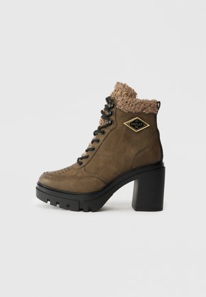 Brown lace-up ankle boots with a chunky black heel and textured fur collar. Features a diamond logo and grooved sole for grip.