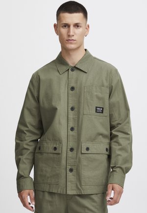 Olive green jacket made of cotton, featuring a collared neck, front button closure, two patch pockets, and a label on the chest pocket.