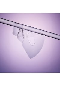 Transparante pleisterstrip die aan een horizontale staaf hangt tegen een zachte paarse achtergrond.