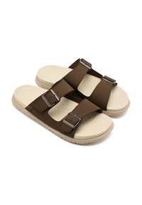 Sandales marron avec deux sangles réglables, ferrures argentées et une semelle en caoutchouc texturée beige. Design plat à bout ouvert avec semelle intérieure rembourrée.