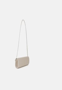 Beige, sylinterimäinen clutch-laukku, jossa on sileä pinta ja ketjuhihna, joka sisältää taitetun läpän suunnittelun ja minimalistisen tyylin.