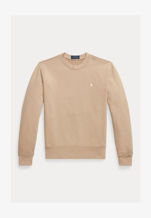 Bézs pulóver kerek nyakkivágással, hosszú ujjakkal és bordás mandzsettákkal. A bal mellkason kis fehér logó található. Simább pamut anyagból készült.