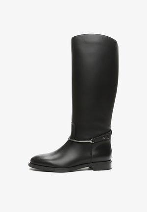 Mustan nahkainen polven yläpuolelle ulottuva saapas, jossa on sileä pinta, pyöreä kärki, minimalistinen hopeiset yksityiskohdat ja litteä pohja.