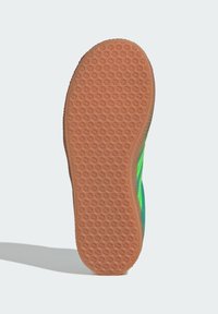 Sulan på en sko med ett texturerat orange gummimönster med små stjärnor och en kurvad kant, kompletterad med en livfull grön sida.