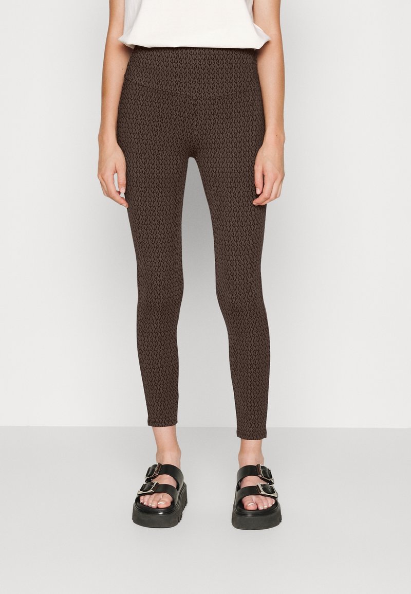 Leggings marrones con estampado y un ajuste elástico, que cuentan con una cinturilla alta. Combinados con sandalias de plataforma negras con detalles de hebilla.