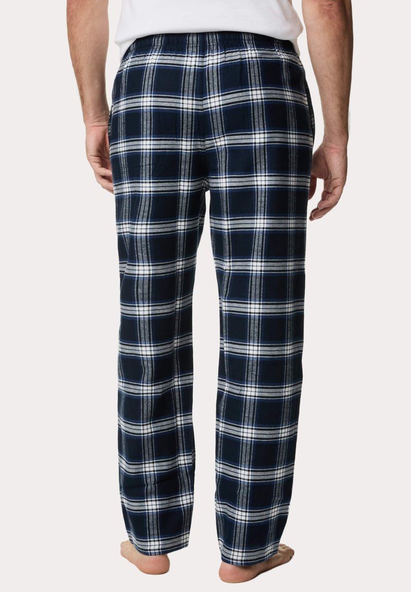Marineblauwe en witte geruite pyjamabroek met een elastische tailleband en rechte pijpen, van een zachte, gestructureerde stof. Blote voeten zichtbaar.